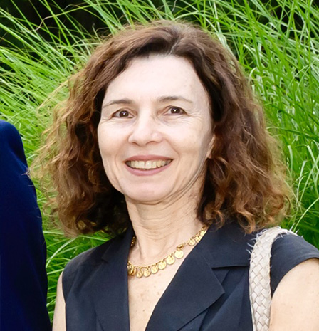 Portrait of Dr. Layla Kamoun smiling warmly while standing outdoors against tall green grass, dressed in a dark sleeveless top and gold necklace, representing expertise and welcoming care – IC Laser Eye