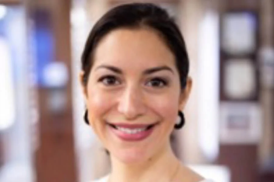 Headshot of Dr. Alessandra Intilli smiling, with dark hair pulled back and wearing small hoop earrings, posed in a softly blurred indoor background that highlights her approachable and professional presence – IC Laser Eye