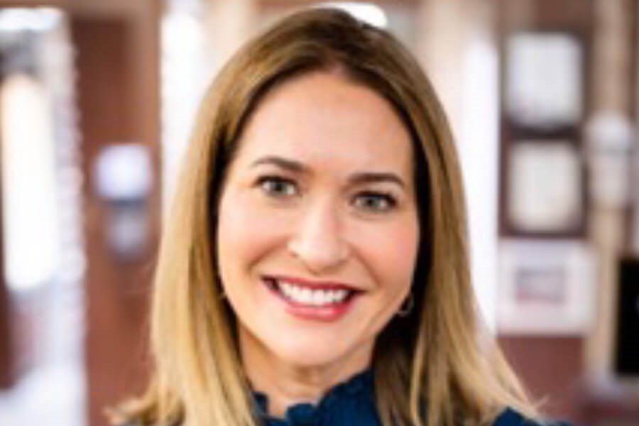 Headshot of Dr. Colleen Halfpenny smiling warmly, with straight light brown hair, wearing a dark top, posed in a softly blurred indoor setting that conveys professionalism and welcoming care – IC Laser Eye