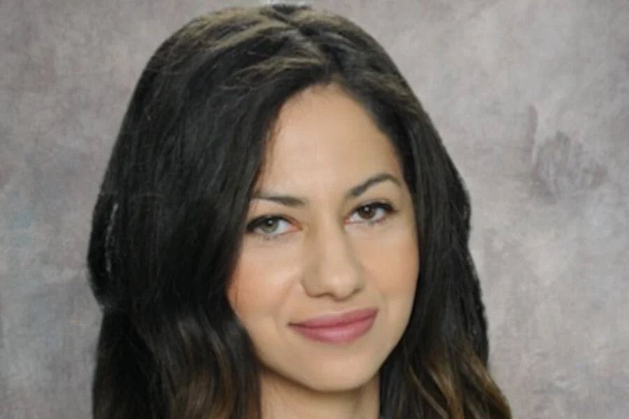 Professional portrait of Dr. Rowan Mahmoud with long dark hair, softly smiling against a neutral gray background, reflecting expertise and compassionate eye care – IC Laser Eye