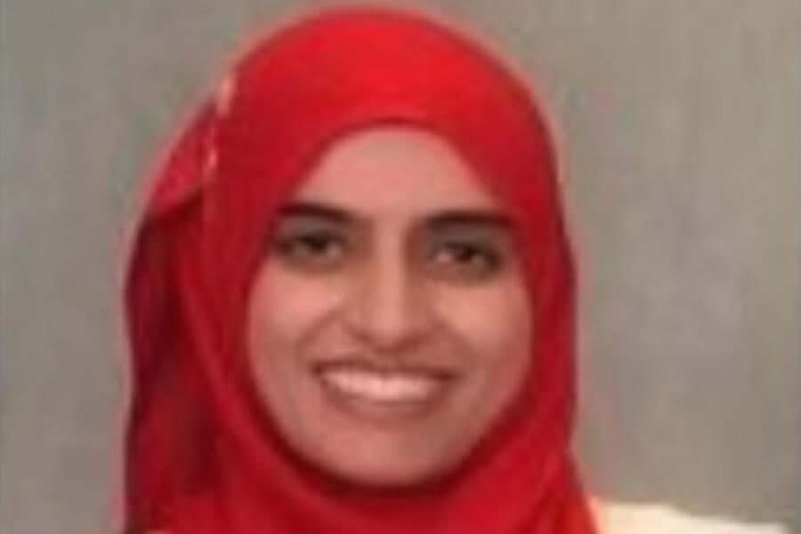 Professional portrait of Dr. Uzma Chaudhry wearing a bright red hijab and smiling warmly against a neutral background, representing compassionate and expert eye care – IC Laser Eye