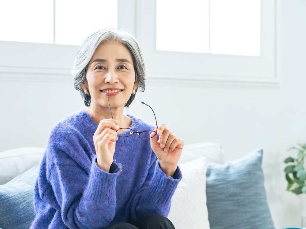A happy older woman holding her glasses, representing improved vision and freedom from corrective lenses after LASIK - LASIK eye surgery Philadelphia
