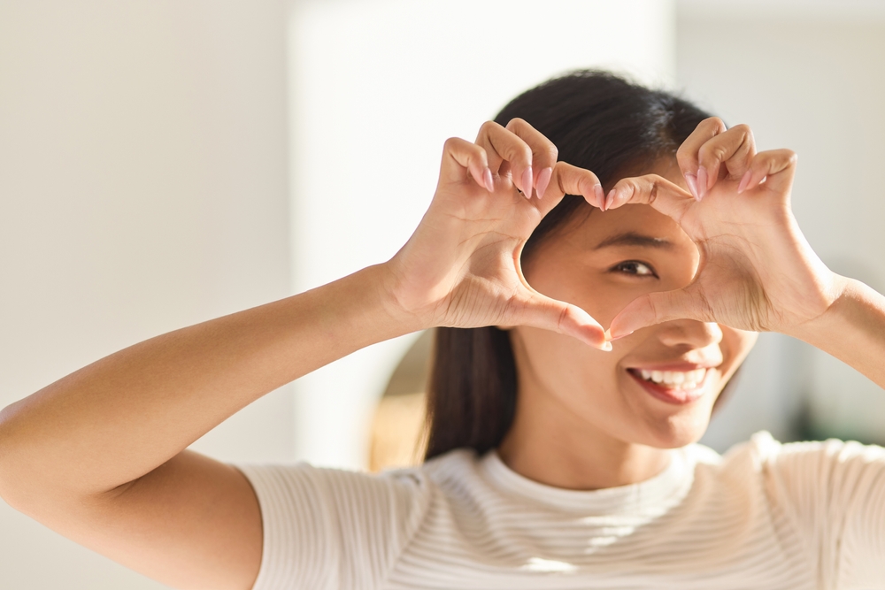 A woman forming a heart shape with her hands over her eyes, symbolizing love for clear vision and successful LASIK results - LASIK eye surgery Philadelphia